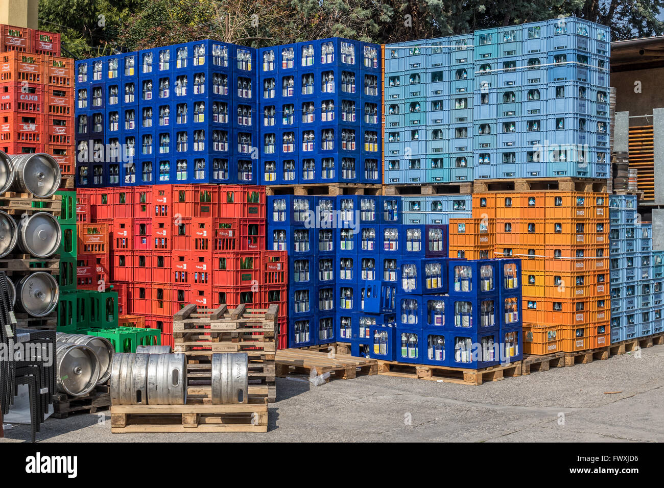 Beer kegs and colorful plastic crates with glass bottles Stock Photo