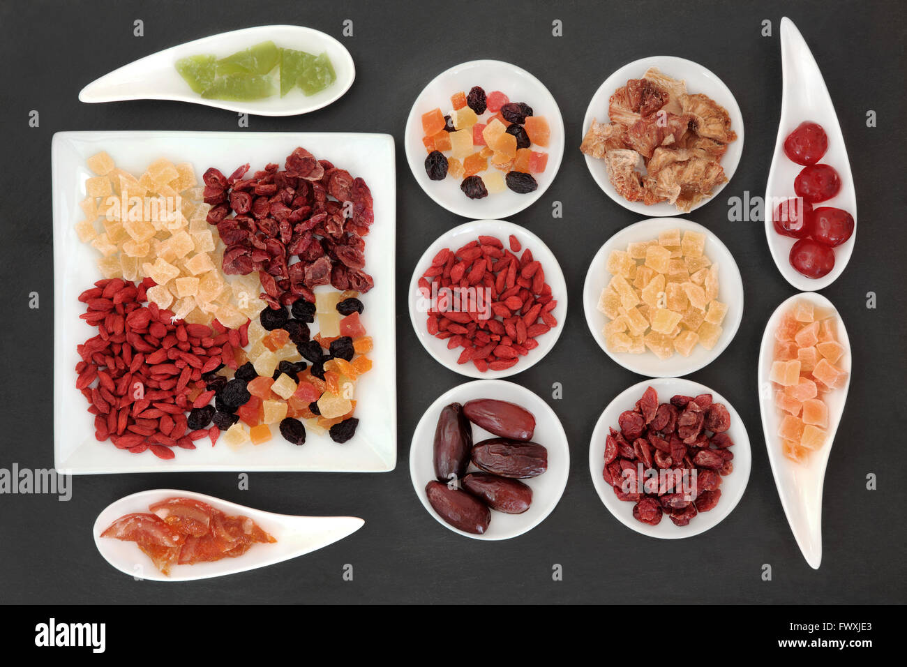 Healthy dried fruit selection in white porcelain bowls over slate background. Stock Photo