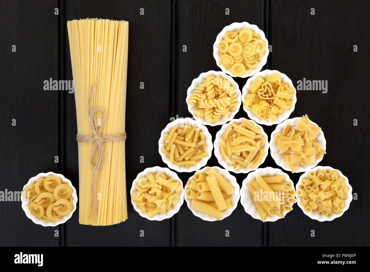 Spaghetti pasta dried food selection in a bundle and in porcelain crinkle bowls  over dark wood  background. Stock Photo