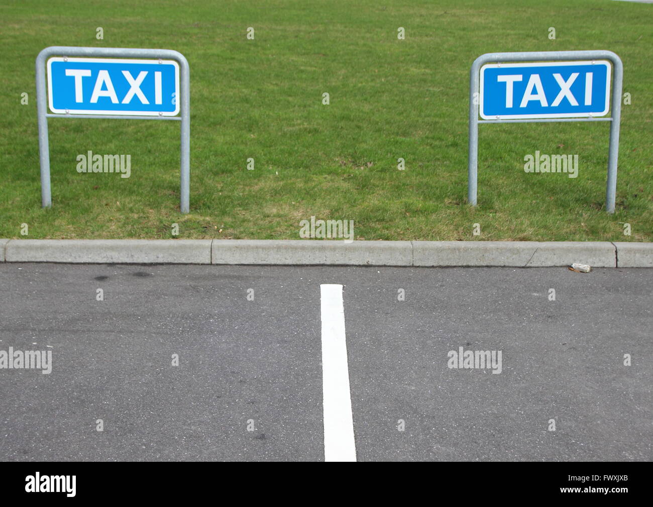 Two Metal Taxi Signs at Empty Parking Place with Green Background Stock Photo