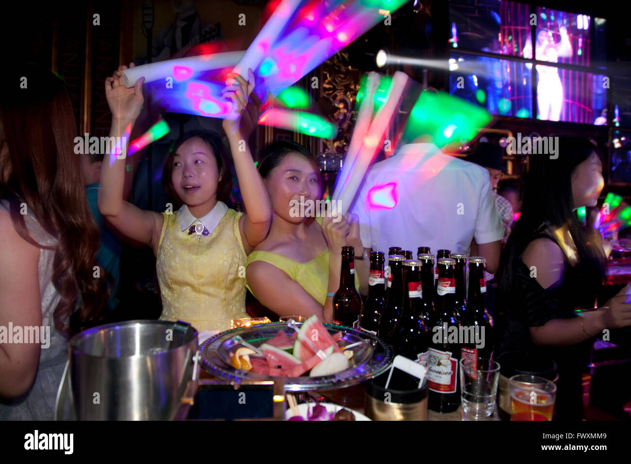Clubbers at a club in China wave light-glow tubes and dance vigorously. Stock Photo