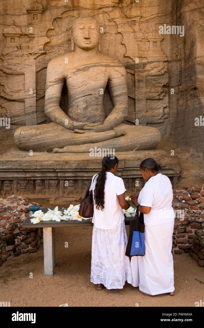 Sri Lanka, Polonnaruwa, Gal Vihara, Dhyana Mudra, women leaving lotus flower offerings Stock Photo