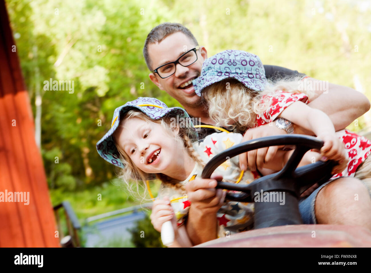 Sweden, Vastra Gotaland, Olofstorp, Father with daughters (4-5, 8-9) driving tractor Stock Photo