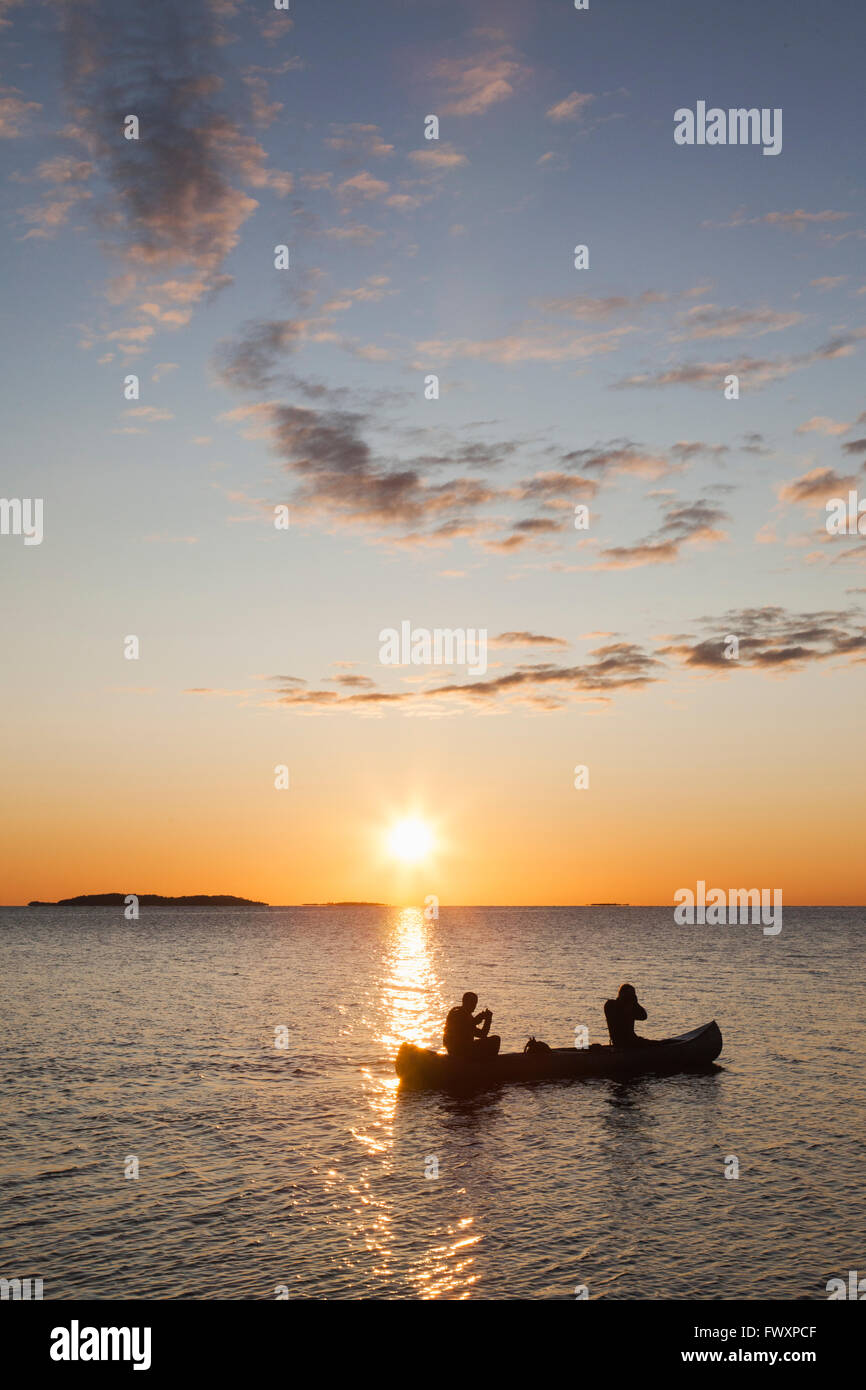Sweden, Medelpad, Sundsvall, Alnon, Two men in canoe on Baltic Sea at sunset Stock Photo