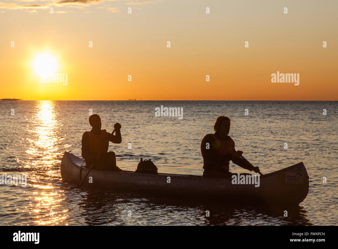 Sweden, Medelpad, Sundsvall, Essvik, Brattberget, Two men in canoe at sunset Stock Photo