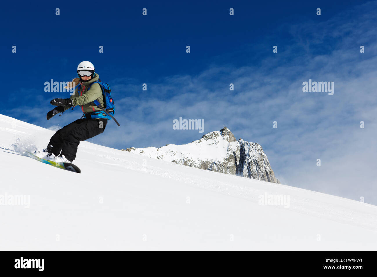 Switzerland, Andermatt, Young woman snowboarding in Alps Stock Photo