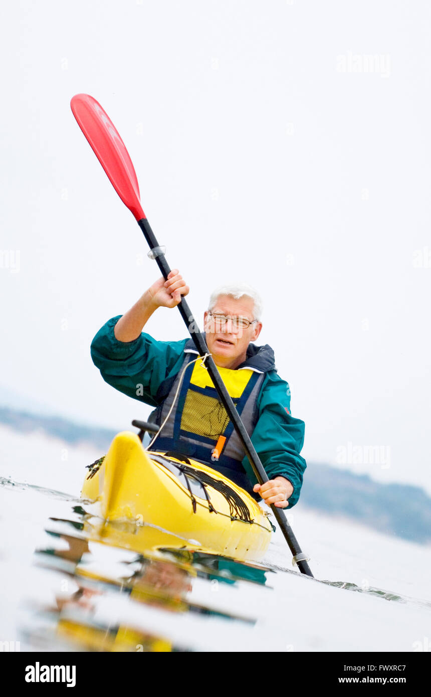 Sweden, Bohuslan, Tjorn, Senior man paddling kayak Stock Photo
