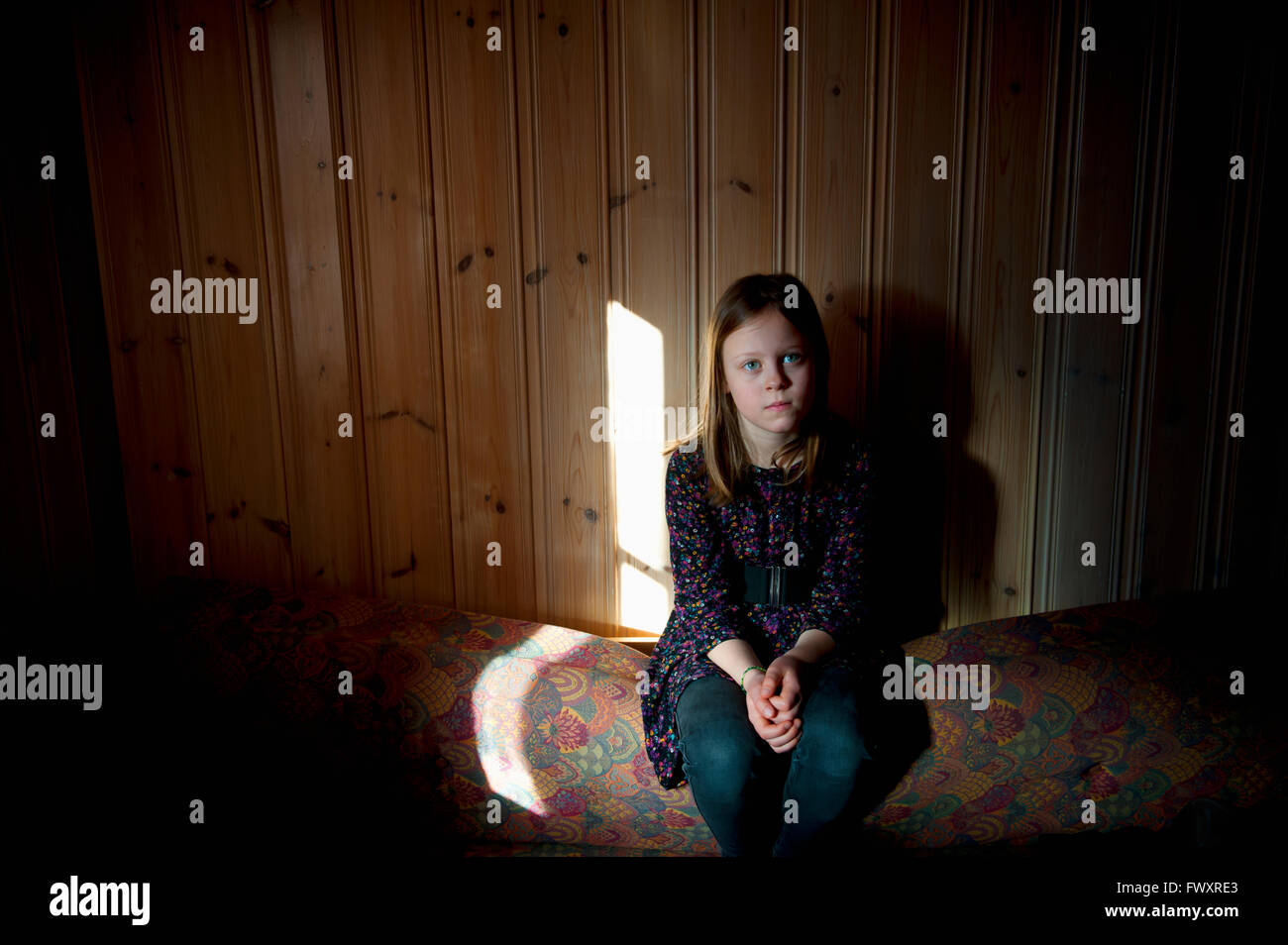 Girl (12-13) sitting against wooden wall Stock Photo