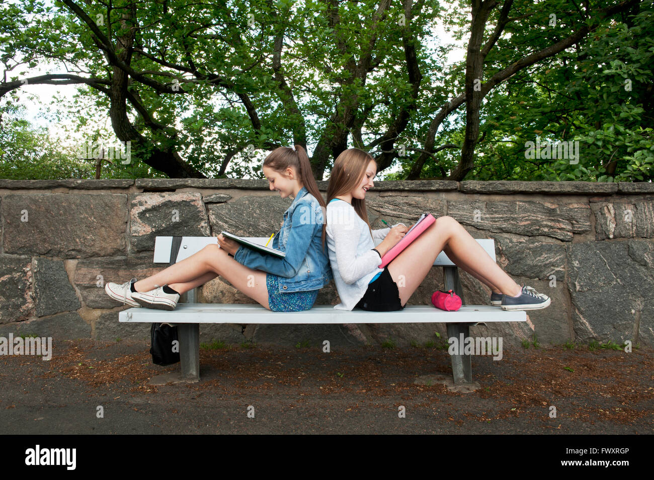 Sweden, Vastra Gotaland, Gothenburg, Two girls (14-15) sitting on bench back to back Stock Photo