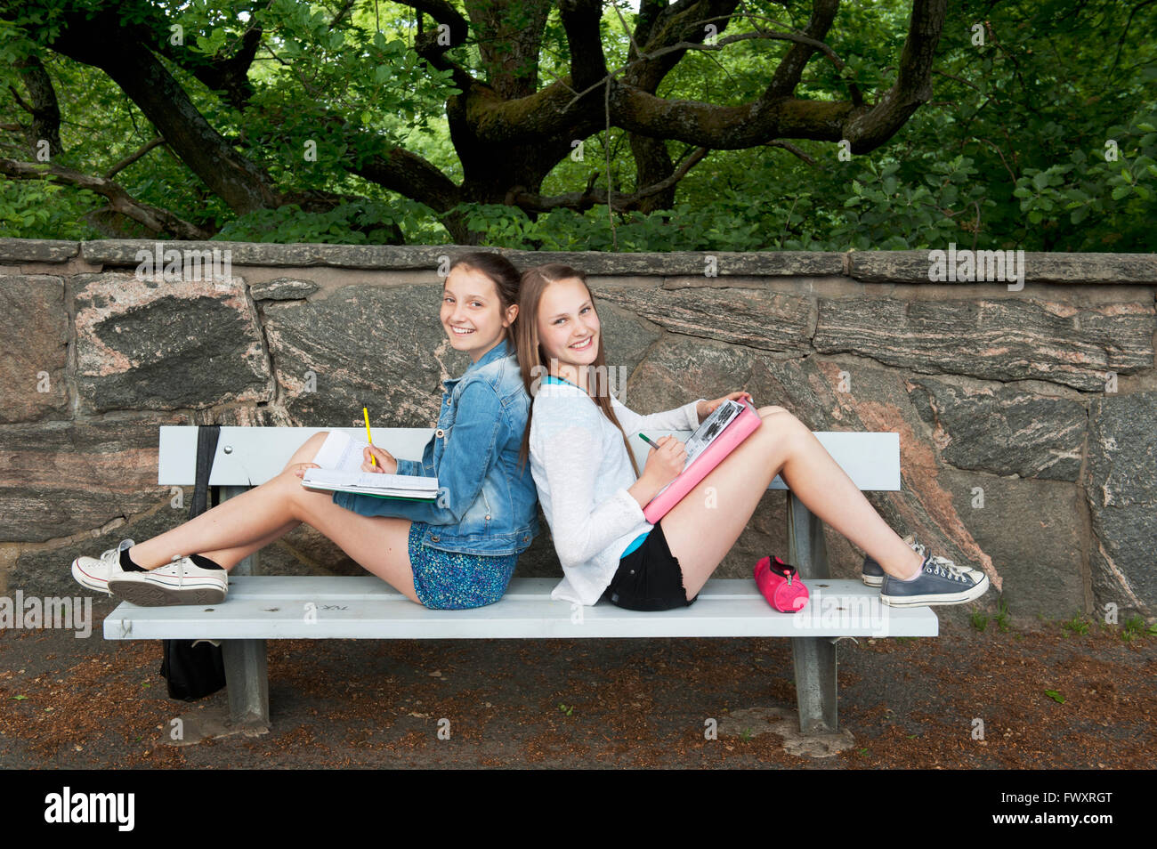 Sweden, Vastra Gotaland, Gothenburg, Two girls (14-15) sitting on bench back to back Stock Photo