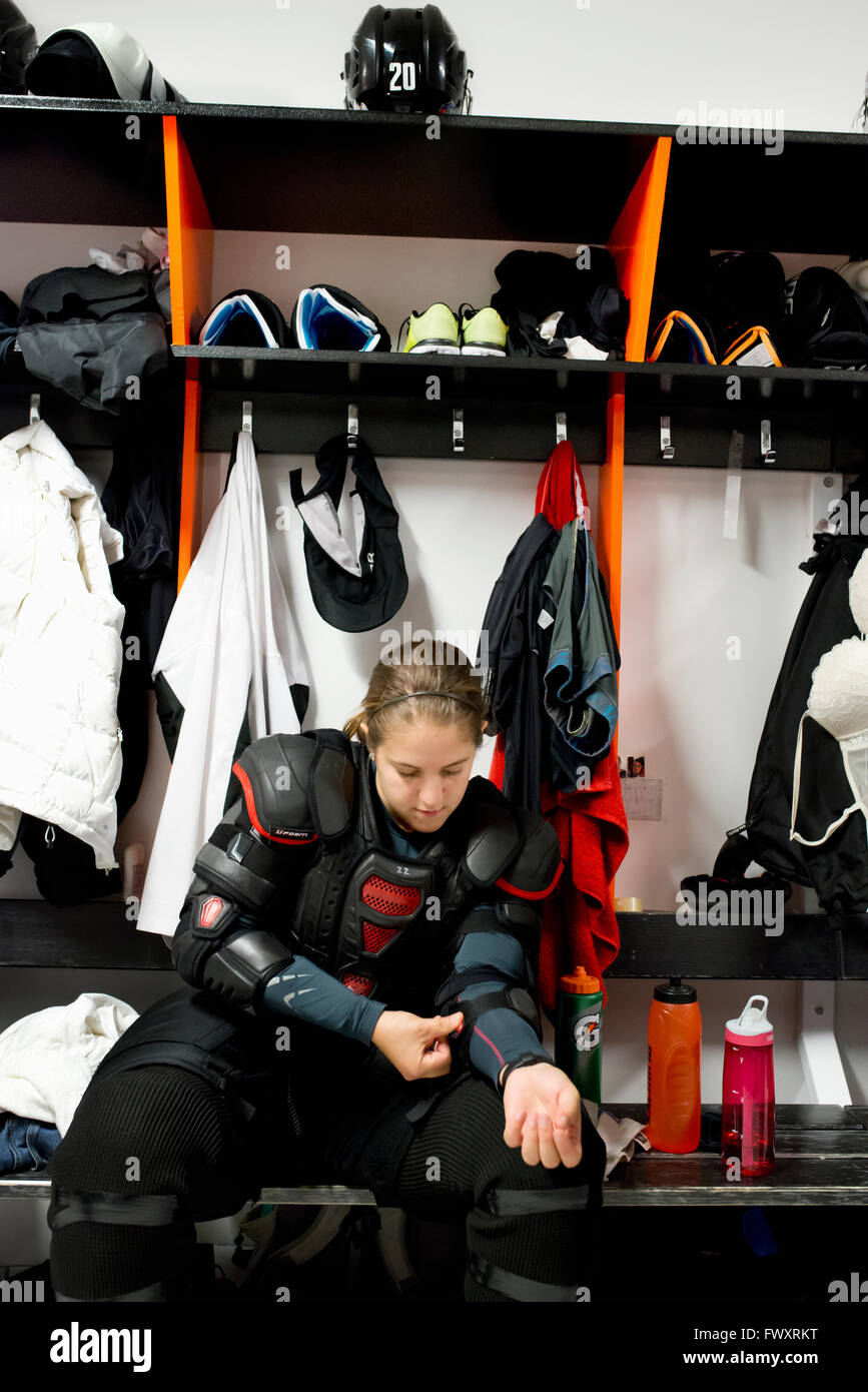 Sweden, Young ice hockey player sitting on bench and getting ready in