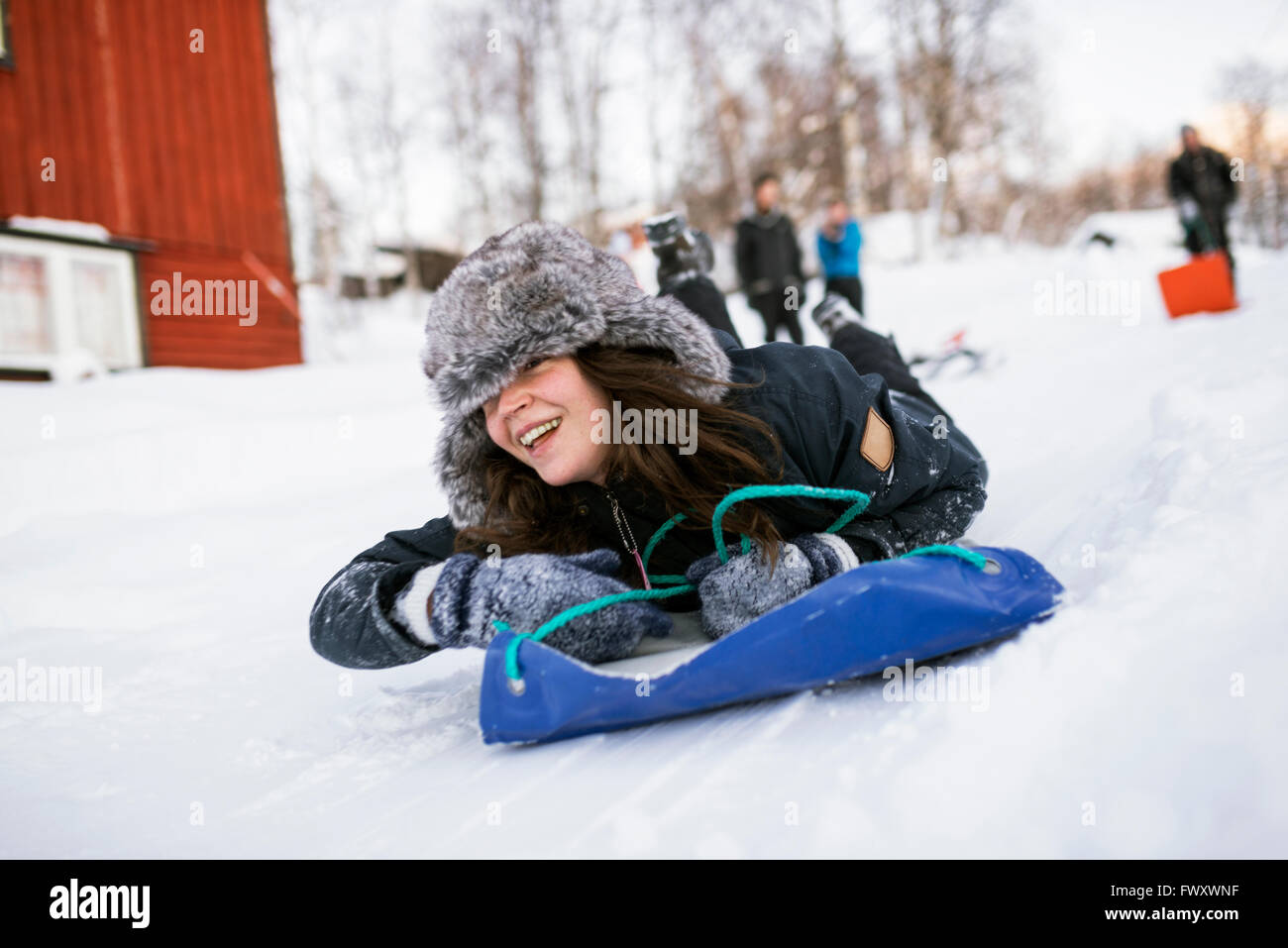 Sweden, Lapland, Hemavan, Young woman sliding on toboggan in winter
