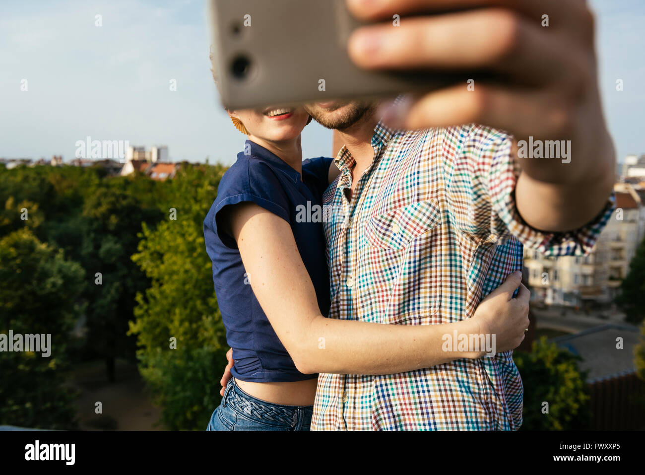 Germany, Berlin, Young couple hugging and taking selfie with smart phone Stock Photo
