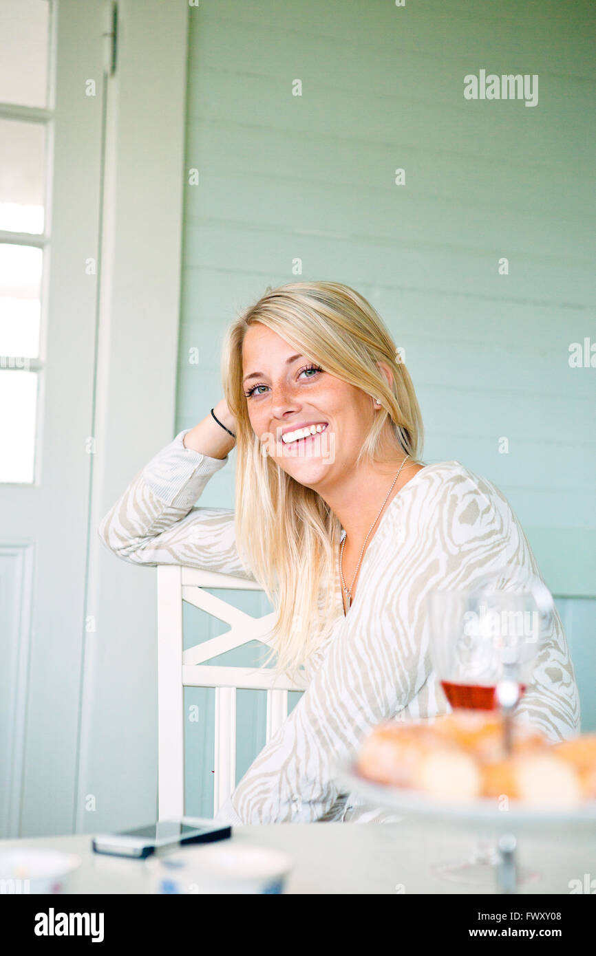 Smiling young woman sitting at table Stock Photo