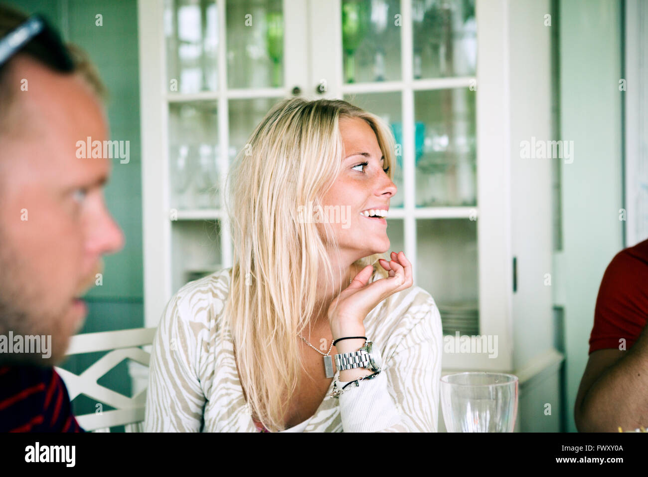 Smiling young woman talking with friends Stock Photo