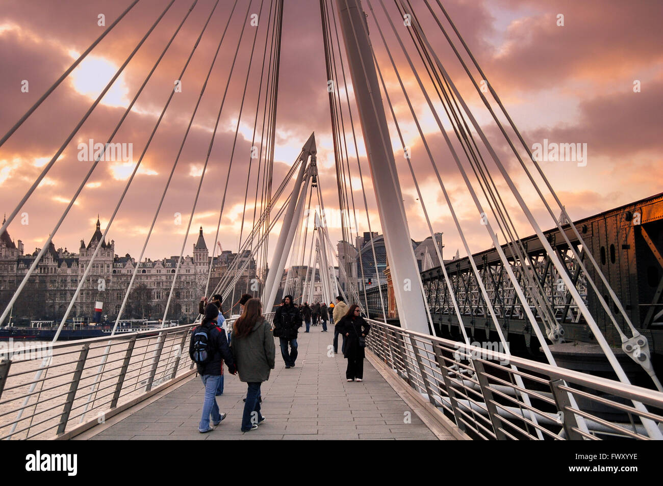 Walking along Golden Jubilee Bridge in London at sunset. Stock Photo