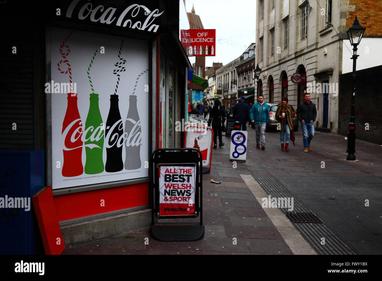 People walking past newsagents shop / off licence, Cardiff, South Glamorgan, Wales, United Kingdom Stock Photo
