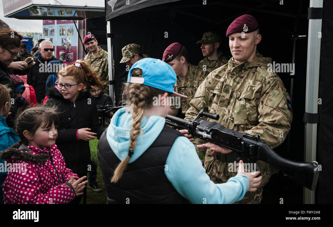 A soldier shows a young girl a machine gun at an emergency services day in Falkirk Stock Photo
