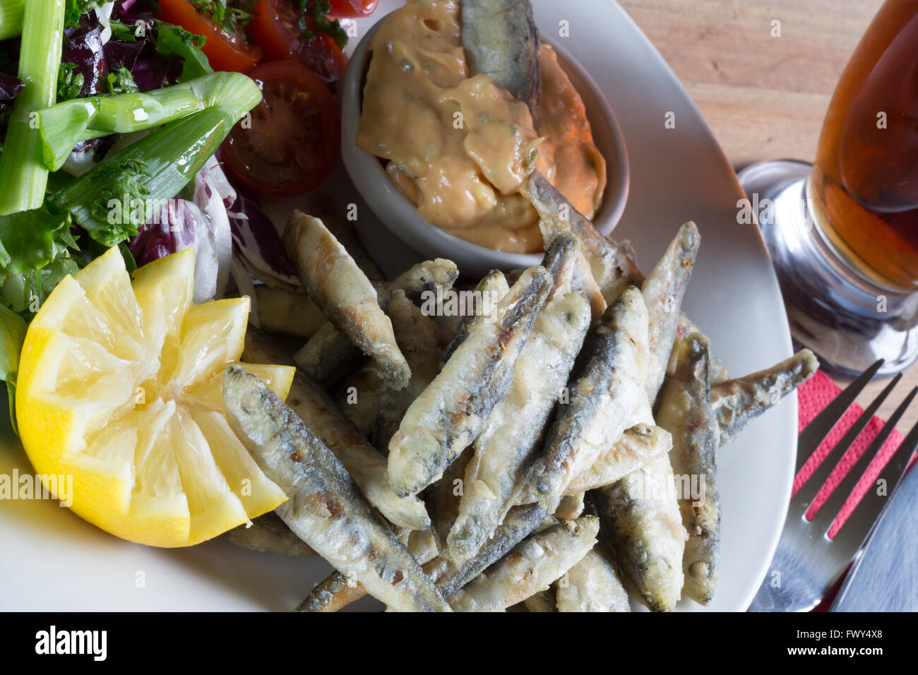 An Entree dish from an English pub/bar menu of fried Whitebait and Marie Rose sauce with a side salad and glass of beer/ale. Stock Photo