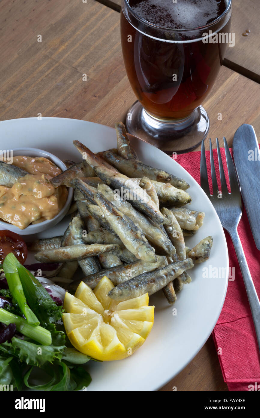 An Entree dish from an English pub/bar menu of fried Whitebait and Marie Rose sauce with a side salad and glass of beer/ale. Stock Photo