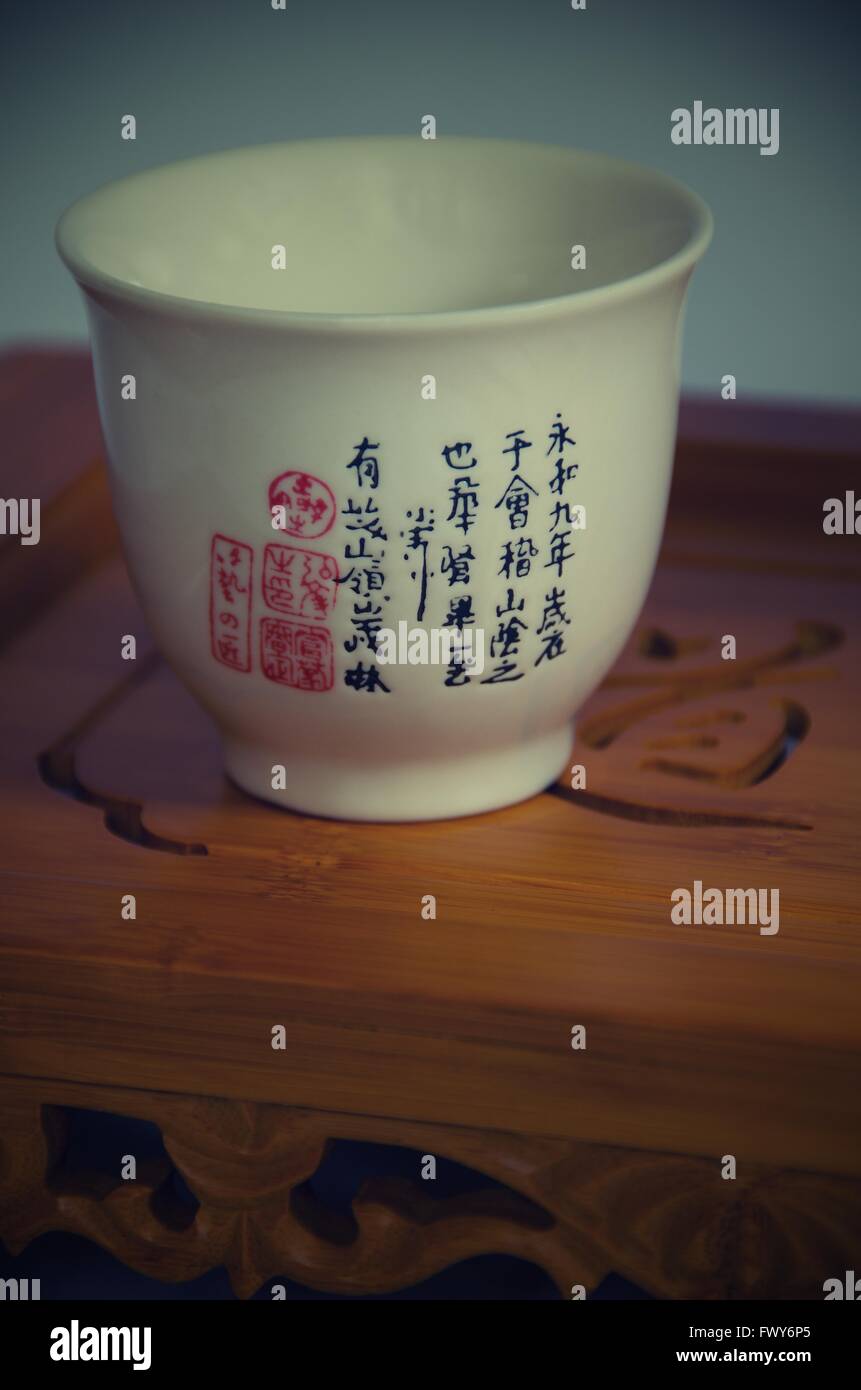 Cup with Chinese symbols, white background and wooden tray Stock Photo