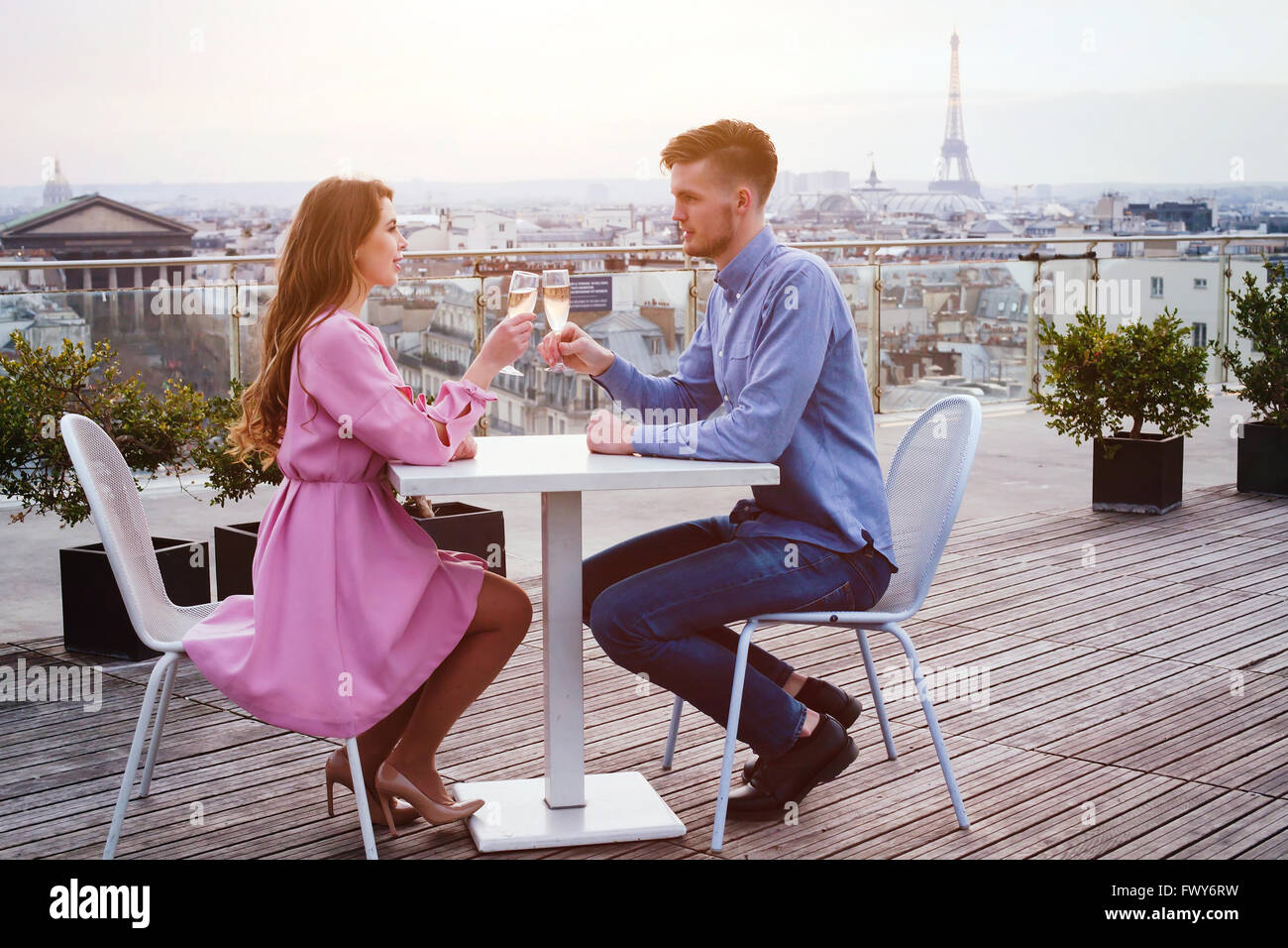 couple drinking champagne in luxury rooftop restaurant in Paris with panoramic view of Eiffel Tower Stock Photo