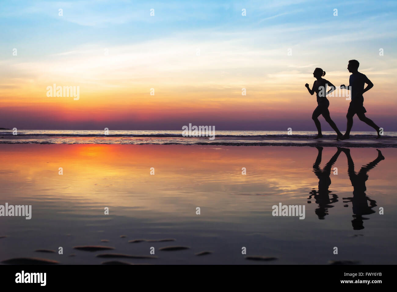 two runners on the beach, silhouette of people jogging at sunset, healthy lifestyle background with copyspace Stock Photo