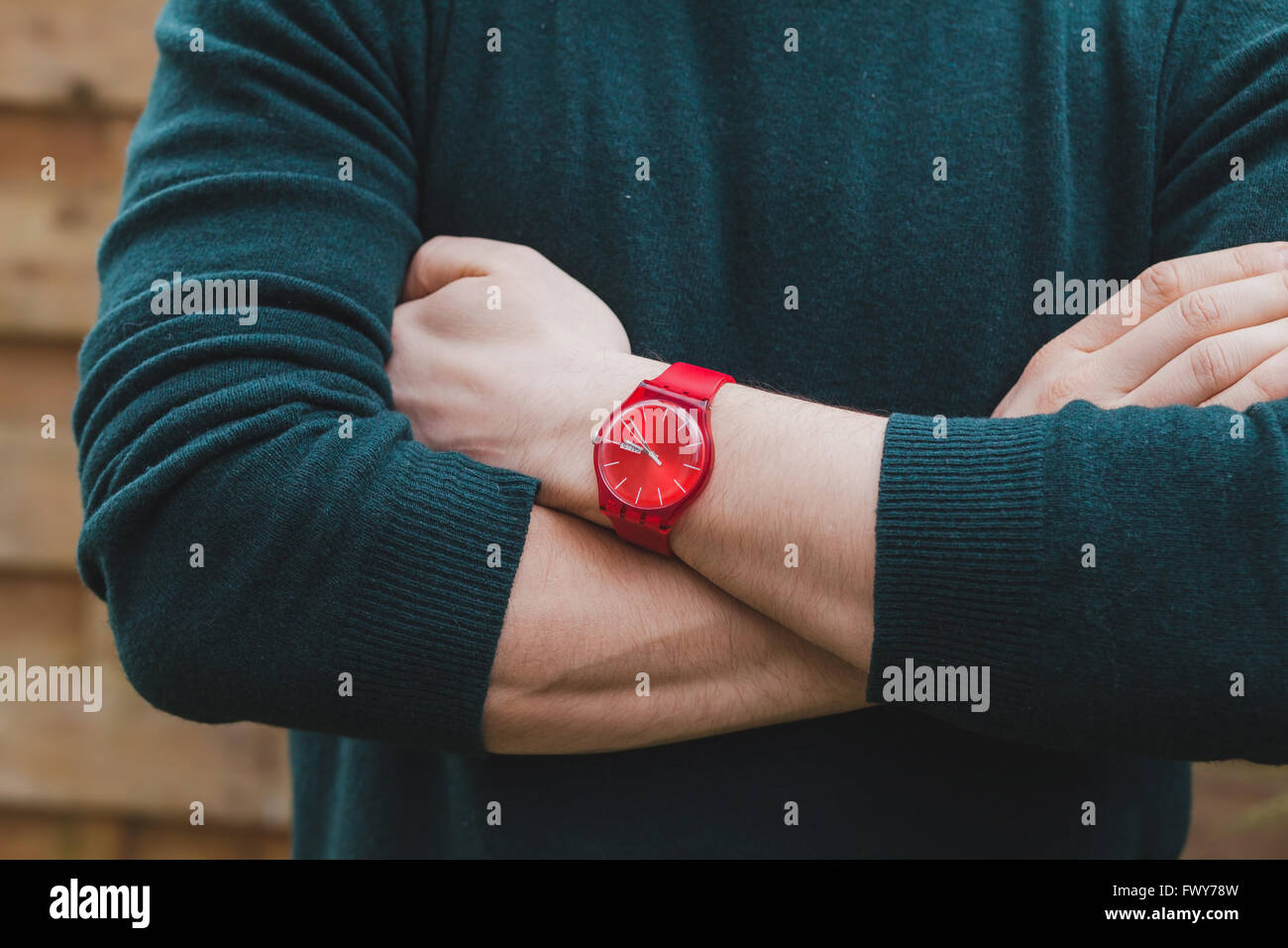 mens fashion, close up of hands of male wearing red watch and green pullover, style concept Stock Photo
