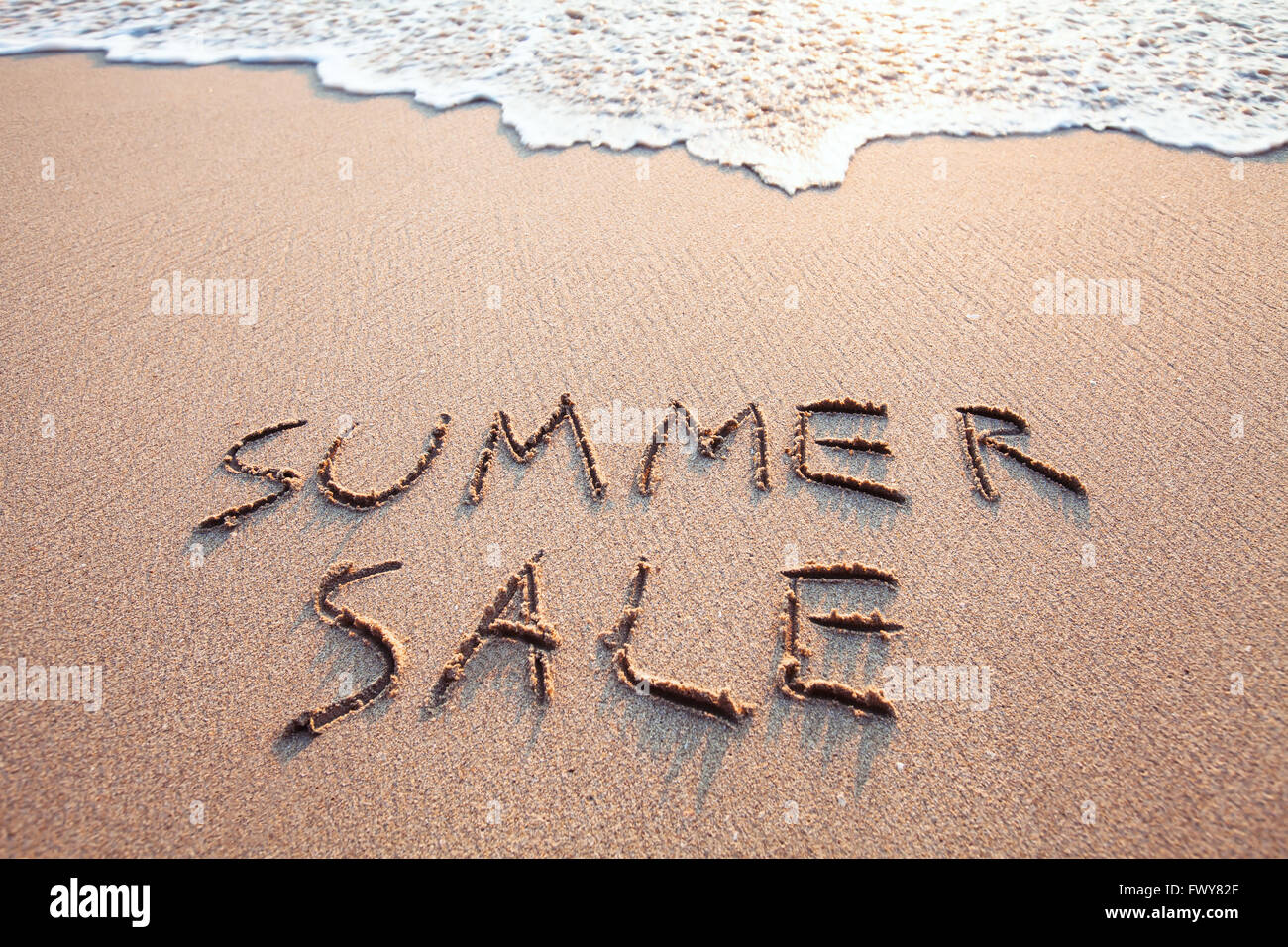 summer sale sign on the beach, text written on the sand Stock Photo