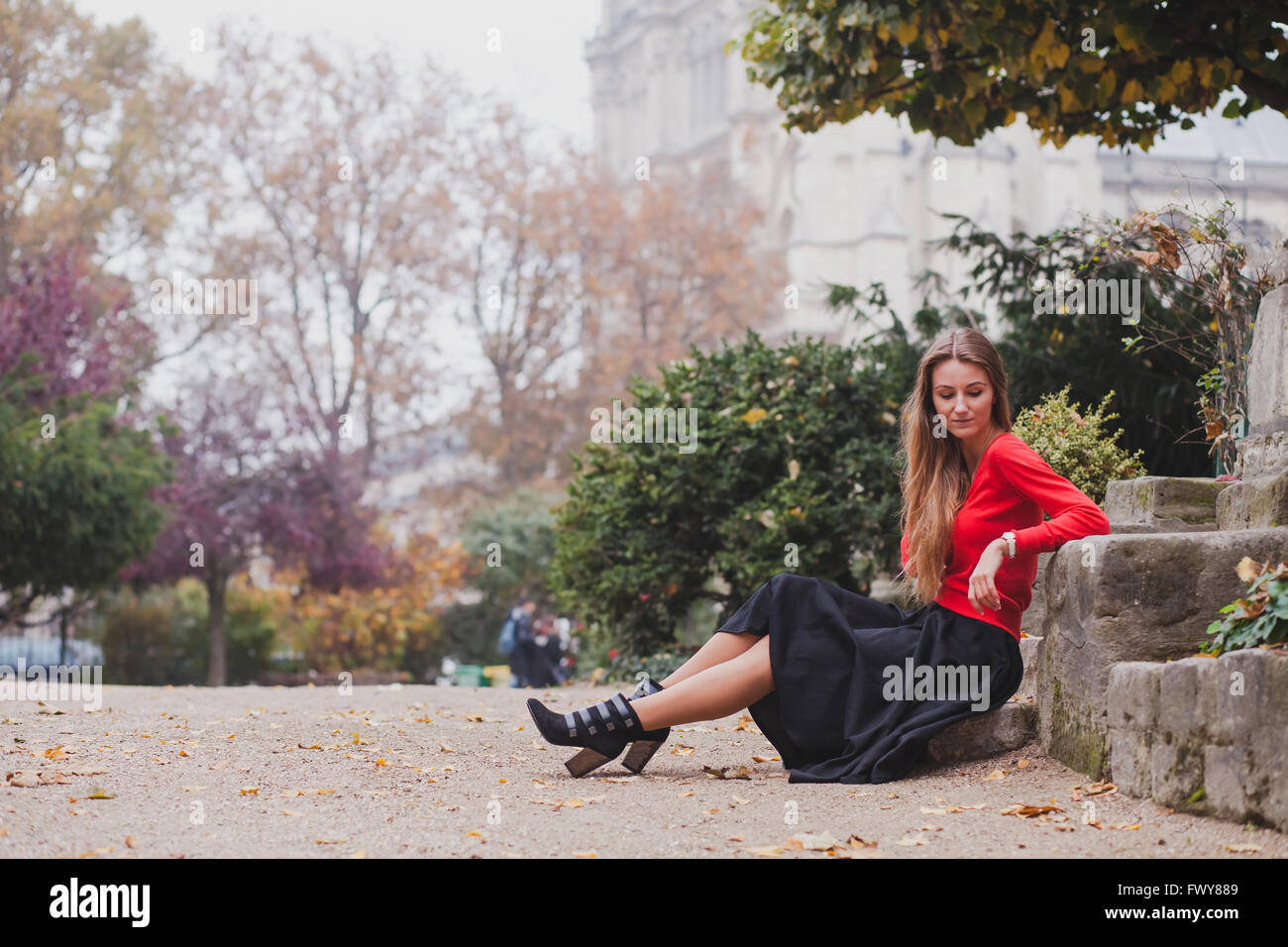 beautiful woman in red, portrait of caucasian fashion young model with long hair sitting alone, psychology concept Stock Photo