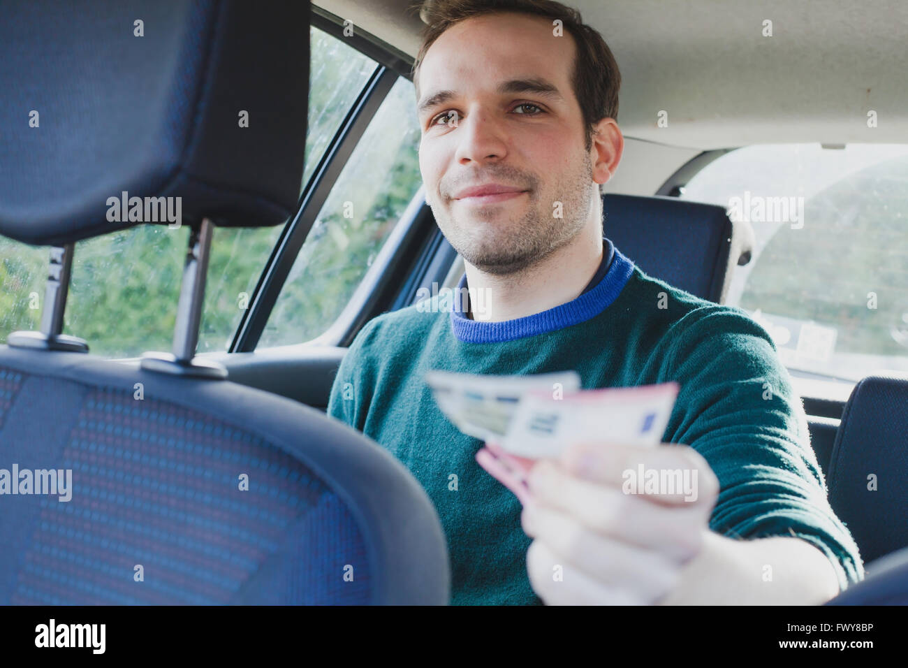 happy passenger in taxi paying by cash Stock Photo