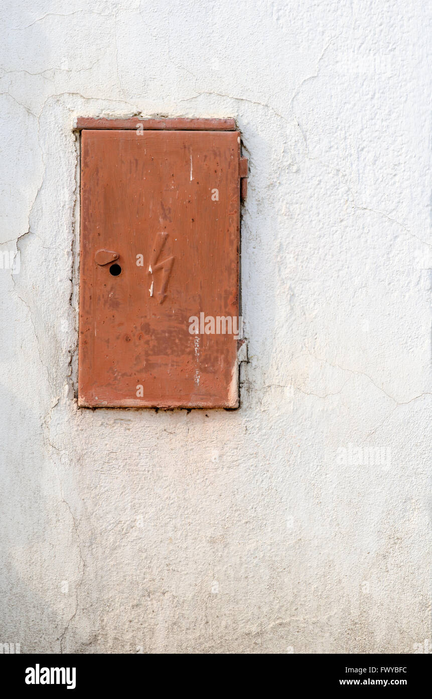Rusty brown iron doors of switchboard on white wall. Stock Photo