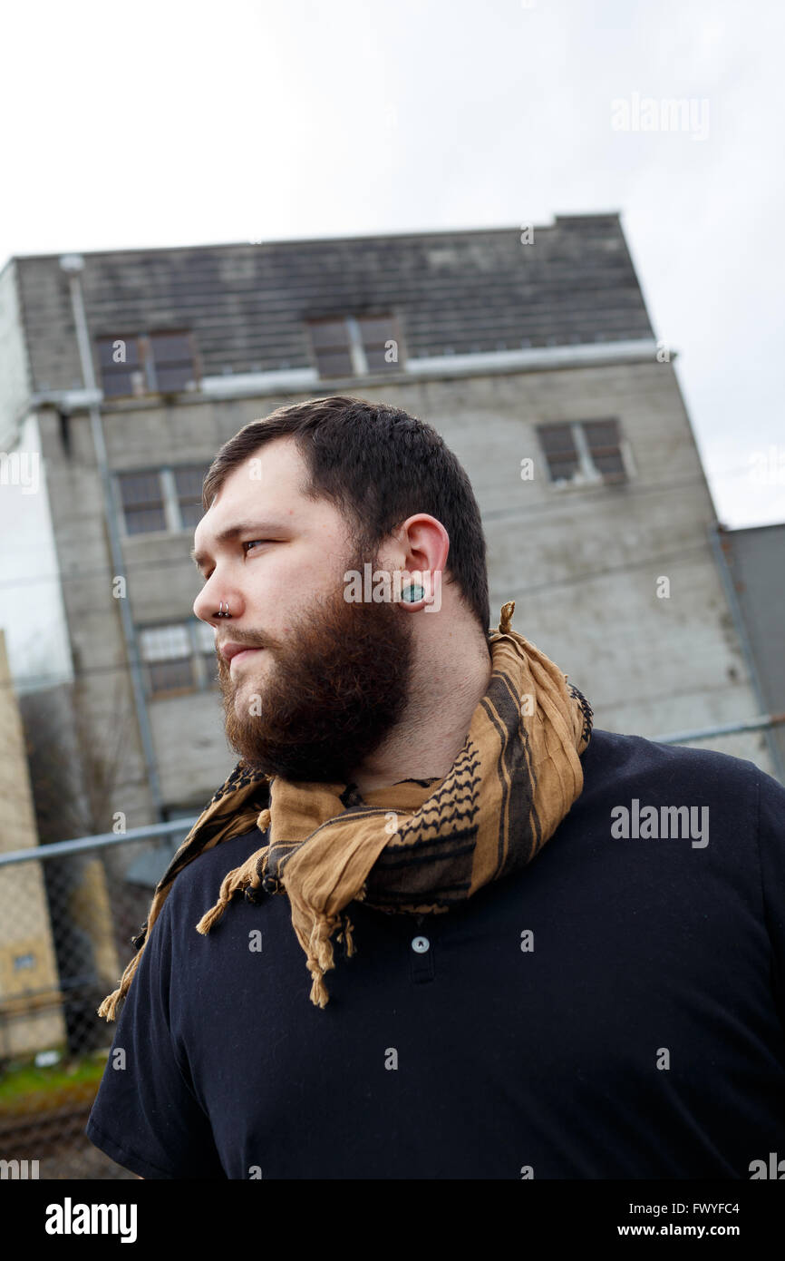 Young adult man outdoors in an urban environment for a lifestyle portrait of a bearded hipster. Stock Photo