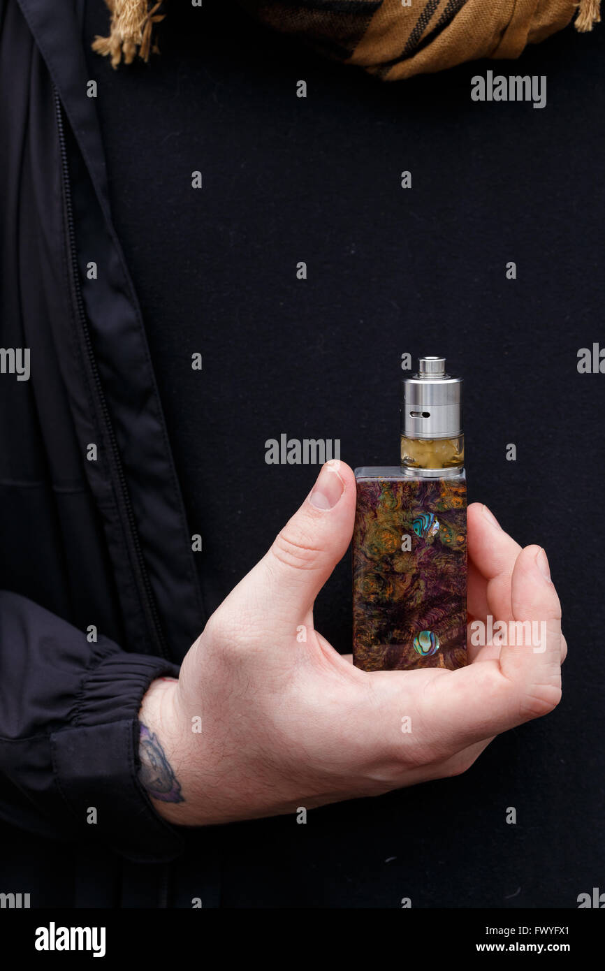 Urban lifestyle portrait of a man vaping in an urban environment with a custom vape mod device. Stock Photo