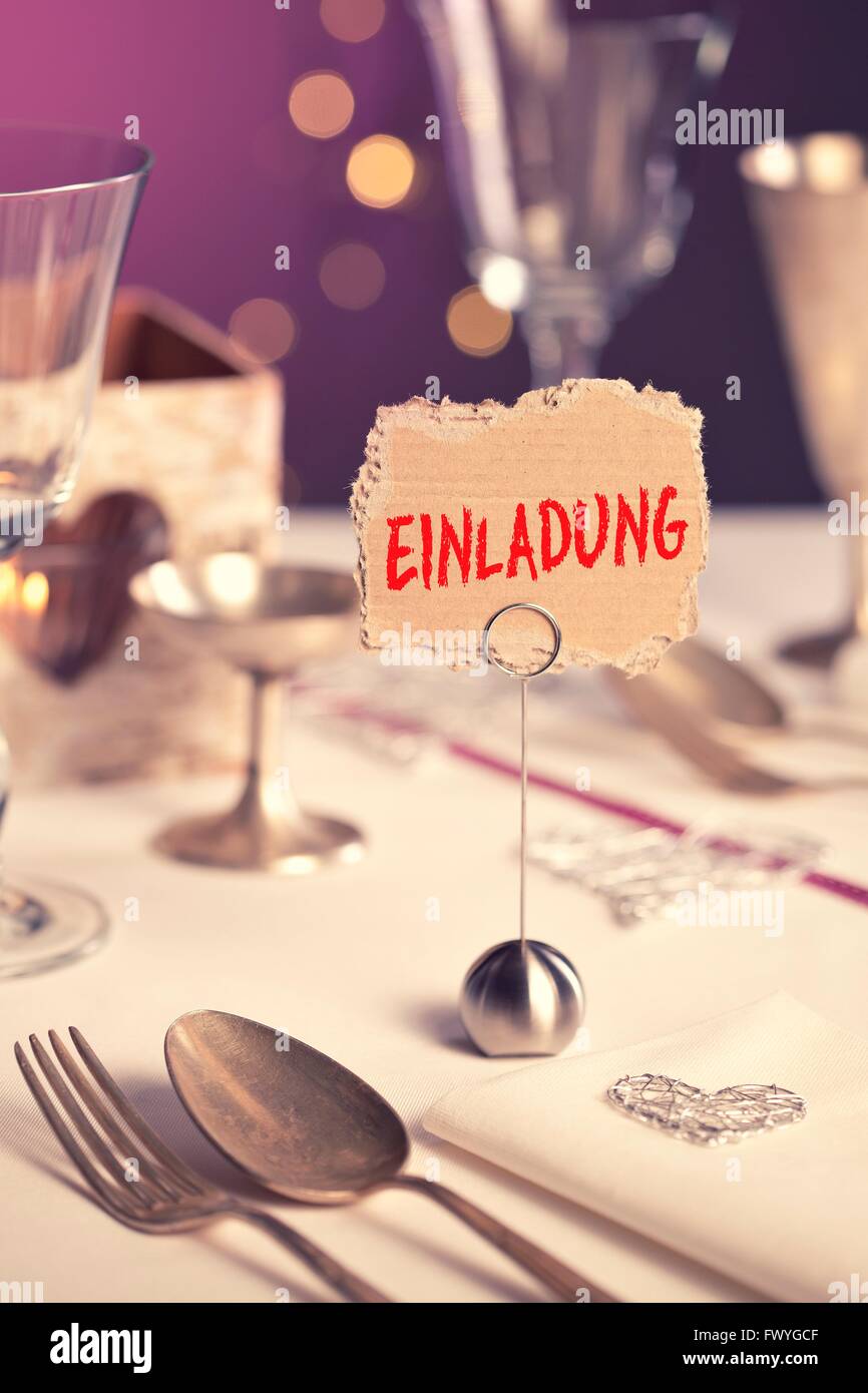Note on festive table with the inscription Einladung or invitation Stock Photo