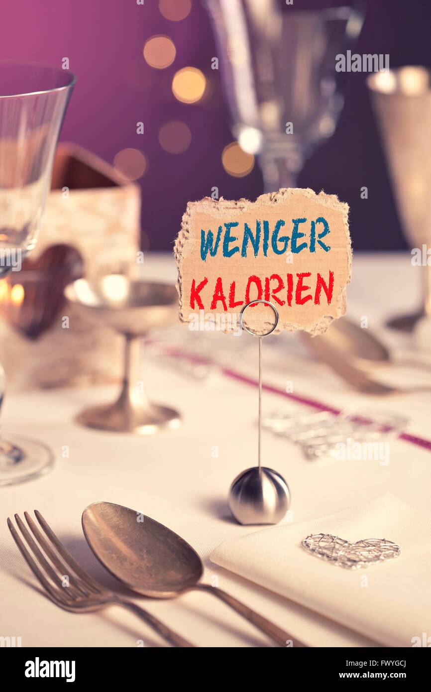 Note on the table that says weniger Kalorien or fewer calories Stock Photo