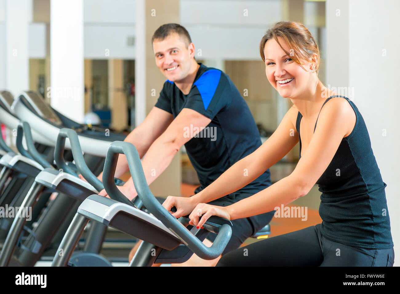 Portrait of a happy couple on a stationary bike in the gym Stock Photo