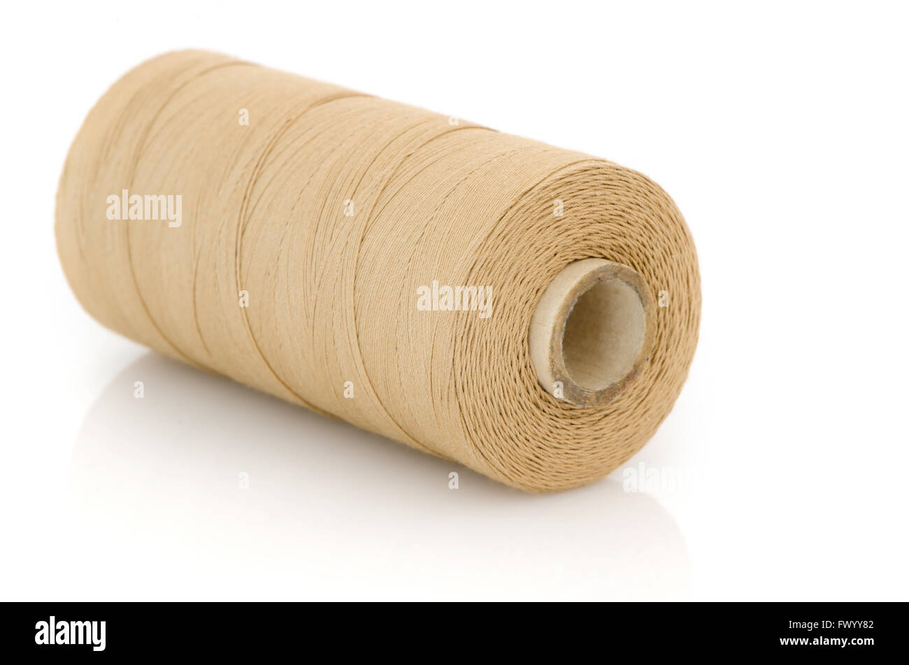 Reel of beige thread isolated on white background. Stock Photo