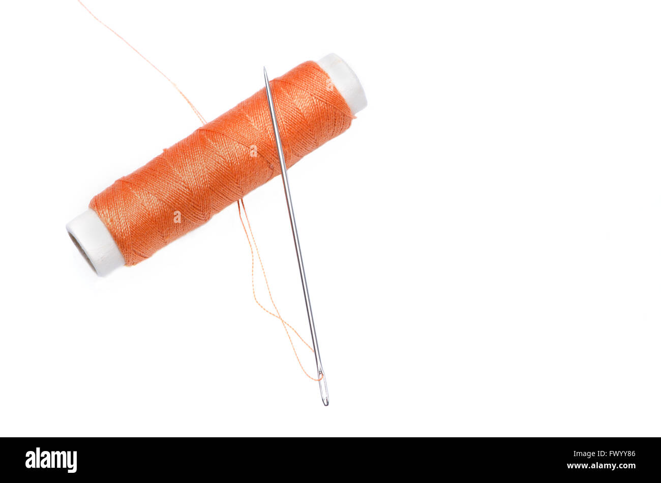 Reel of orange thread and needle isolated on white background. Stock Photo