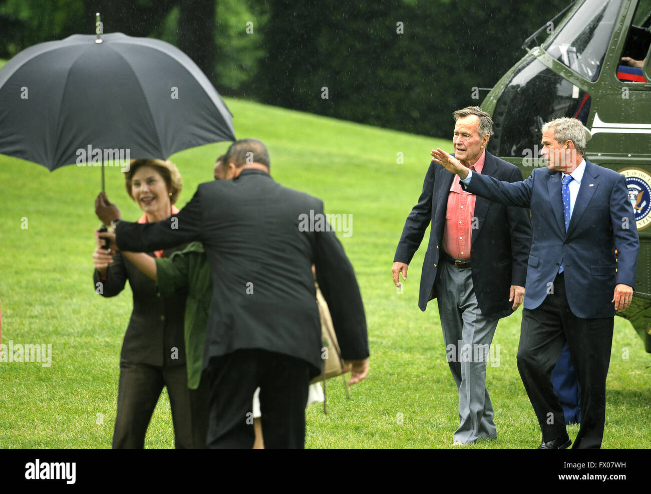 Washington, District of Columbia, USA. 11th May, 2008. Former United States President George H.W. Bush (2nd, R) walks with US President George W. Bush as an aide assists first lady Laura Bush with an umbrella as they arrive at the White House from a weekend at the Crawford, Texas ranch, 11 May 2008 in Washington, DC. Bush, whose daughter Jenna married Henry Hager at the ranch, described the experience as 'spectacular' and 'it's all we could have hoped for'. Credit: Mike Theiler/Pool via CNP © Mike Theiler/CNP/ZUMA Wire/Alamy Live News Stock Photo
