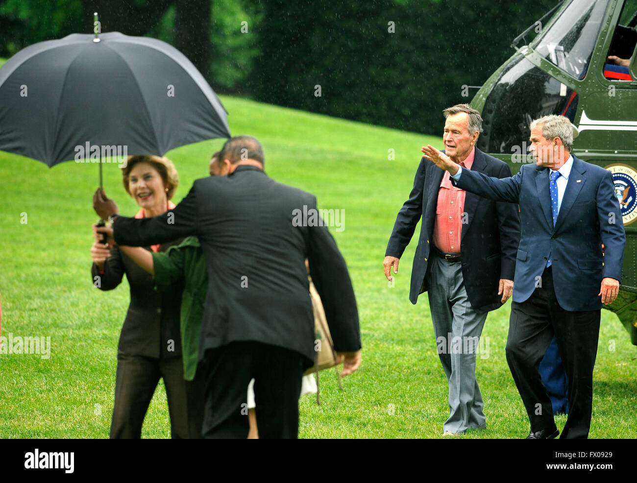 Former United States President George H.W. Bush (2nd, R) walks with US President George W. Bush as an aide assists first lady Laura Bush with an umbrella as they arrive at the White House from a weekend at the Crawford, Texas ranch, 11 May 2008 in Washington, DC. Bush, whose daughter Jenna married Henry Hager at the ranch, described the experience as 'spectacular' and 'it's all we could have hoped for'. Credit: Mike Theiler/Pool via CNP - NO WIRE SERVICE - Stock Photo