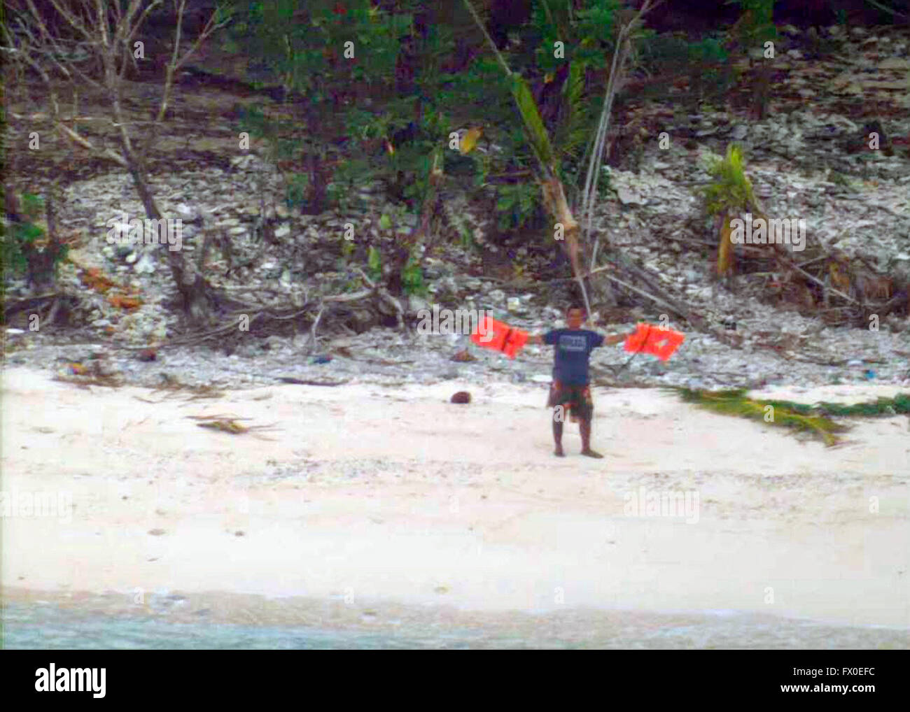 Three men are rescued from the uninhabited island of Fandadik after being located by a Navy aircraft waving life jackets next to a help sign made of palm fronds on the beach April 8, 2016 in Fanadik, Federated States of Micronesia. The men's 19-foot skiff capsized after setting out to sea and spent the night swimming until they arrived at the deserted island. Stock Photo