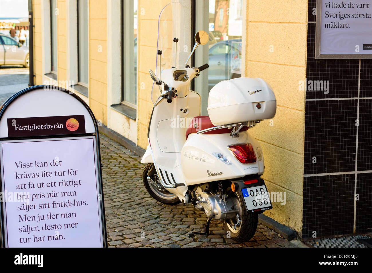 Simrishamn, Sweden - April 1, 2016: Parked Vespa moped with Fastighetsbyran logo on side, parked outside their office in the cit Stock Photo