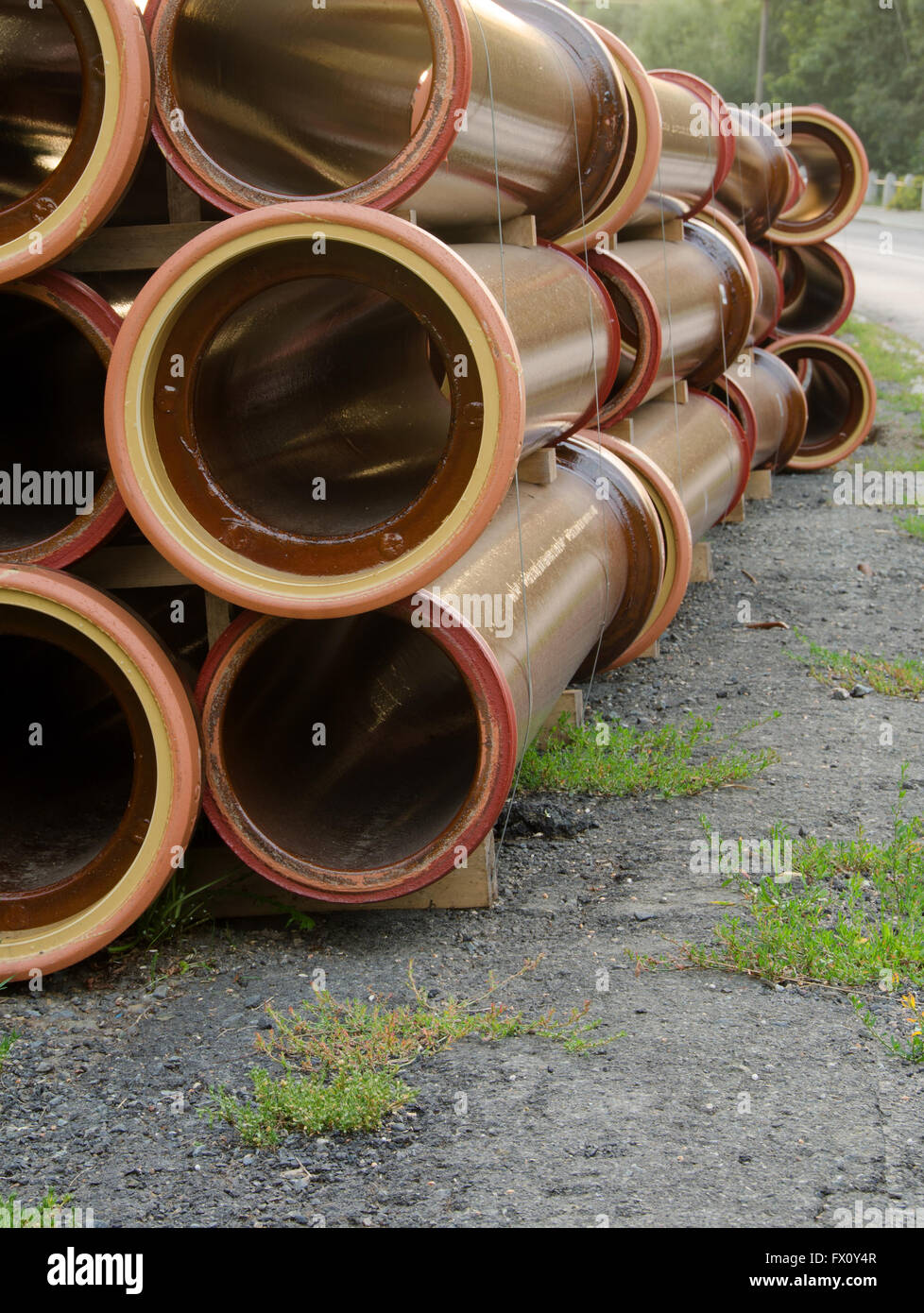 Stack of brown water pipes on the road. Stock Photo