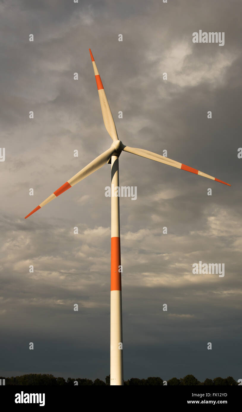 Red and white wind turbine against a dark sky Stock Photo