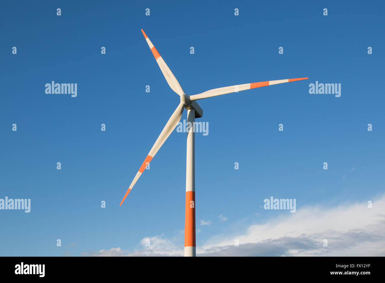 Red and white wind turbine against a blue sky Stock Photo