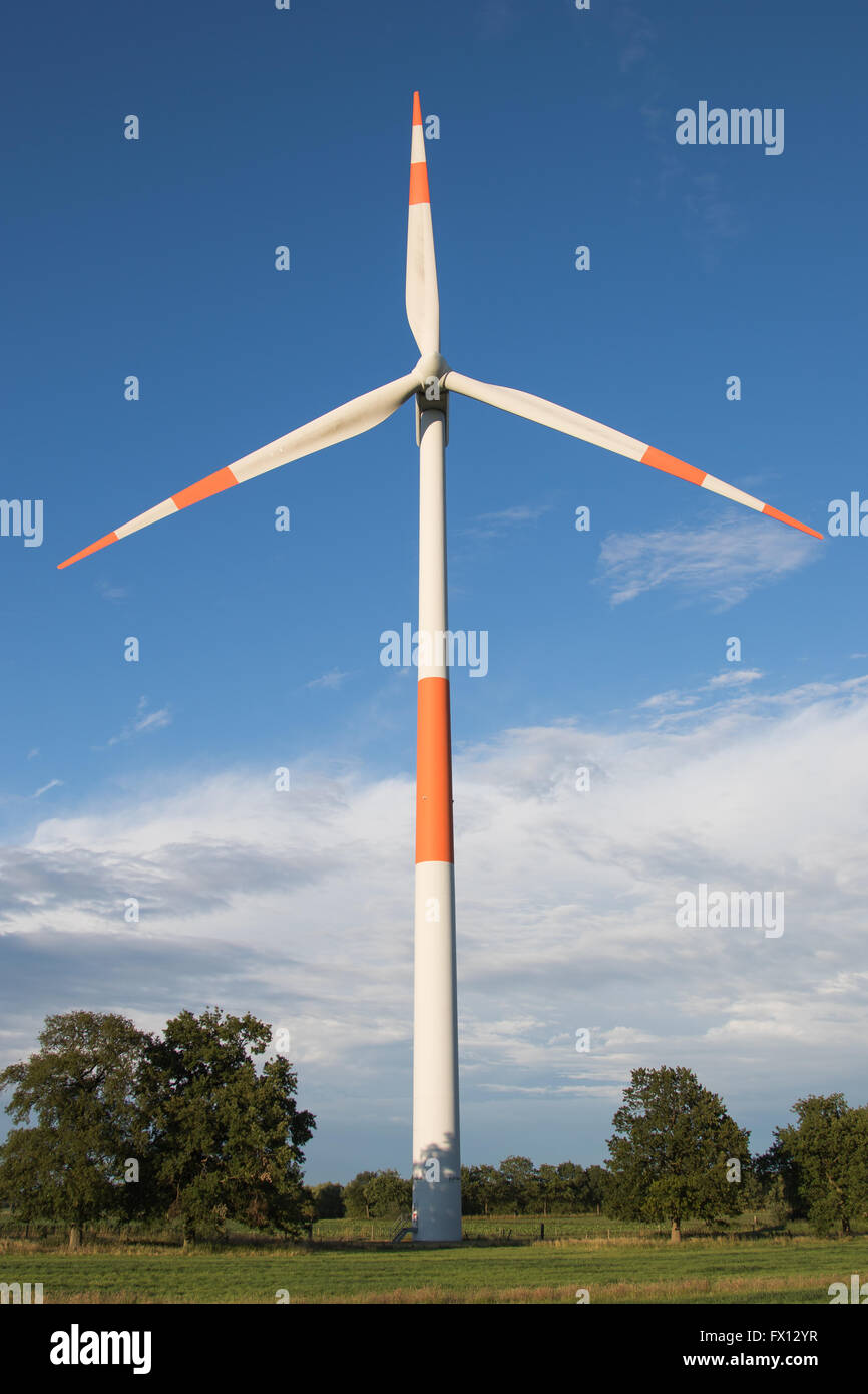 Red and white wind turbine against a blue sky Stock Photo