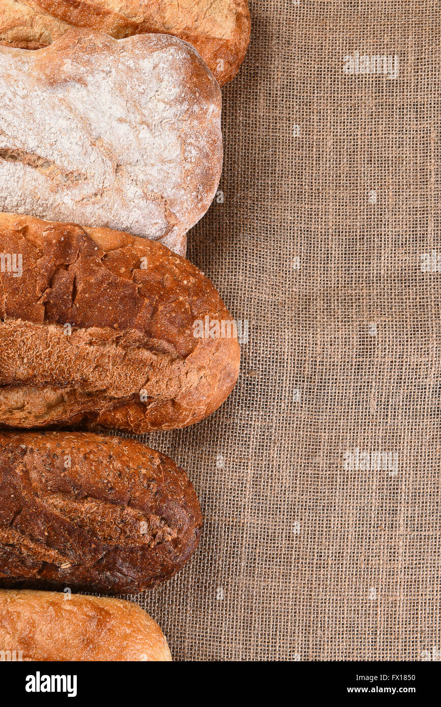 Five different loaves of bread on a wood table with copy space. Vertical format. Stock Photo