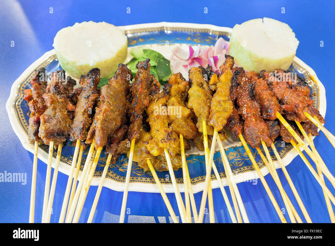 Satay Chicken Beef and Mutton with Cucumbers Onions and Rice Cake Closeup Stock Photo