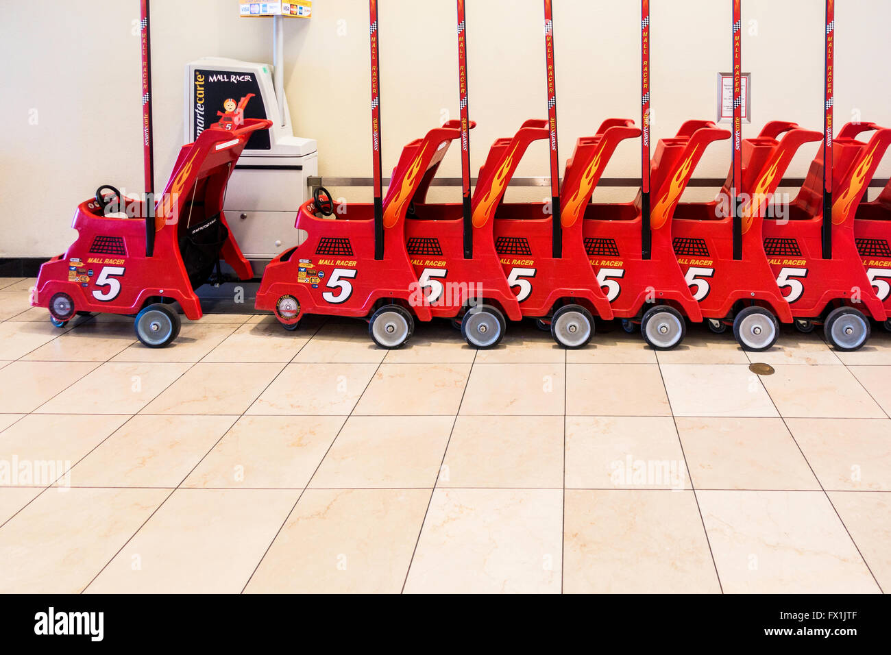 Red rental child strollers lined up in a shopping mall in Oklahoma City, Oklahoma, USA. Side view. Stock Photo